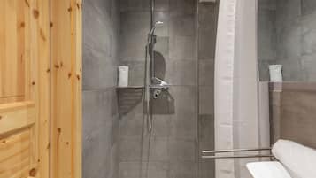 Eine Dusche mit Glastür, grauen Fliesen und einem Holzpaneel an der Seite.