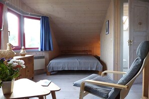A small, cozy room with a single bed, a chair, a table, and a window with curtains. - Ferienhaus im Ferienpark Mirow (Granzow)
