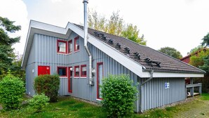 A two-story building with a sloped roof, a chimney, and a small attached structure with a parking sign.