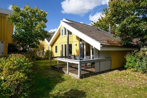 Ein gelbes Haus mit überdachter Veranda und kleinem Garten.
