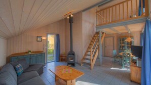 A cozy interior with a wooden staircase, a sofa, a table, and a fireplace. - skandinavisches Ferienhaus in Mirow (Granzow)