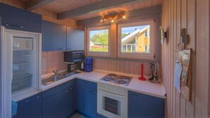 A compact kitchen with a refrigerator, microwave, stove, and sink. - skandinavisches Ferienhaus in Mirow (Granzow)