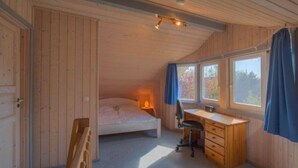 A bedroom with a bed, desk, chair, and windows. - skandinavisches Ferienhaus in Mirow (Granzow)