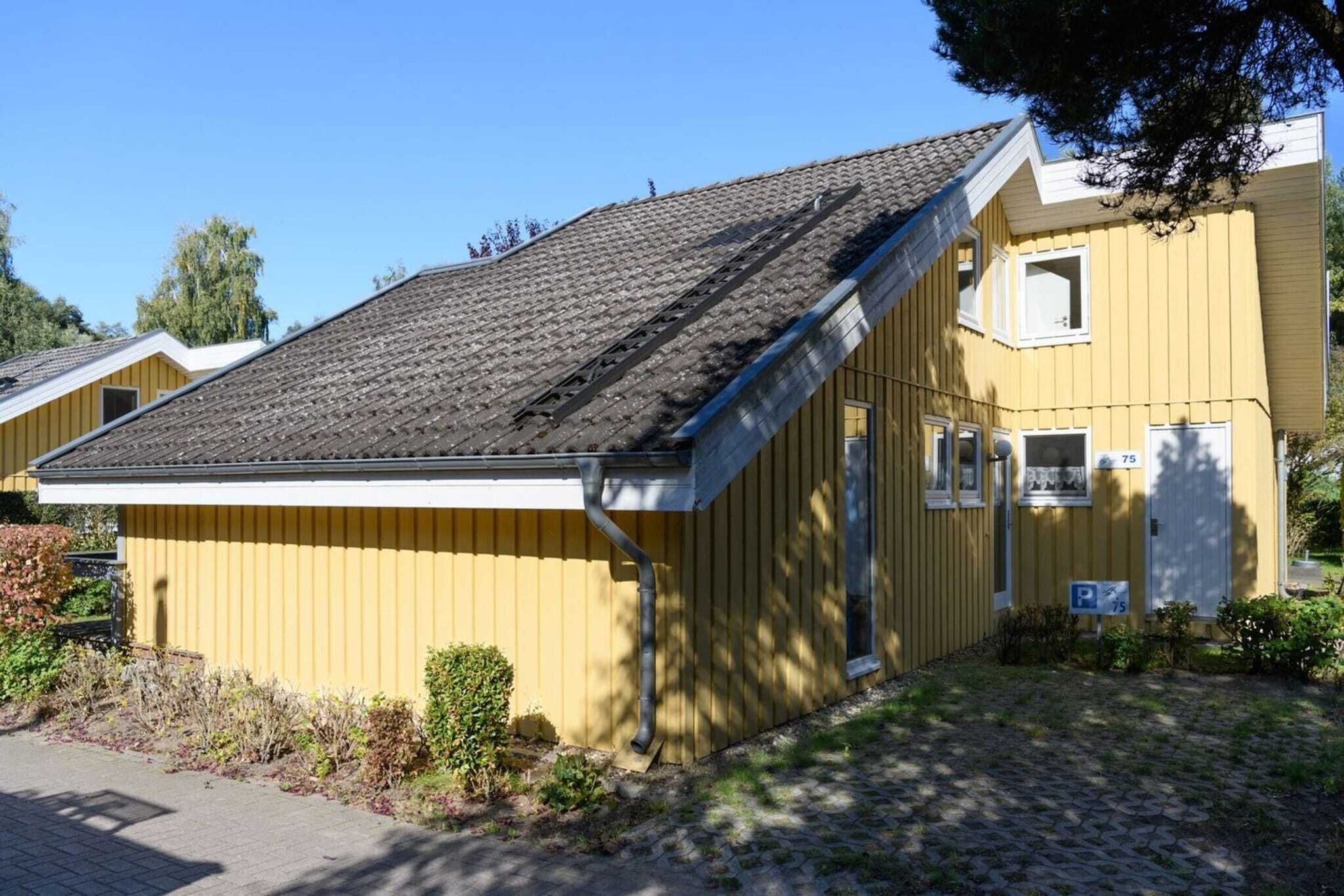 Ein gelbes Gebäude mit geneigtem Dach, einer Garagentür und einem kleinen Vorbereich.