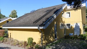 Un bâtiment jaune avec un toit en pente, une porte de garage et un petit porche.
