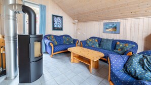 A cozy room with a sofa set, a wooden table, and a black stove. - exklusives skandinavisches Ferienhaus (Granzow)