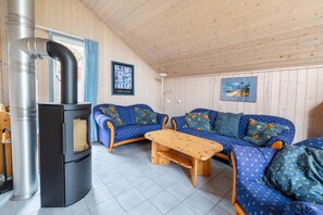 A cozy room with a sofa set, a wooden table, and a black stove.
