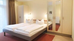 A double bed with white linens, a wardrobe with a mirror, and a red carpet. - Elegant eingerichtete Ferienwohnung (Granzow)