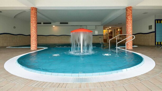 A swimming pool with a central water feature and steps leading into the pool. - Elegant eingerichtete Ferienwohnung (Granzow)
