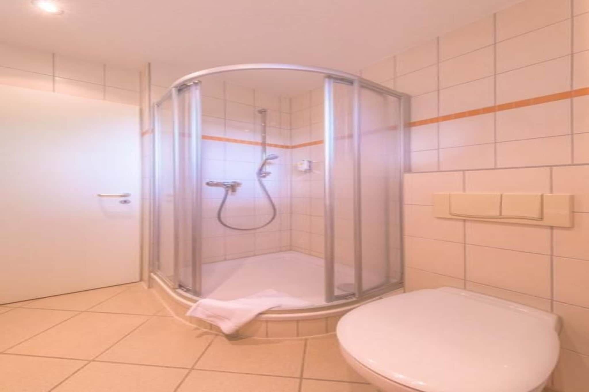 A bathroom with a glass-enclosed shower, a white toilet, and tiled walls.