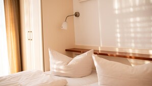 Ein Hotelzimmer mit einem ordentlich bezogenen Bett, einem Nachttisch und einer Wandlampe.