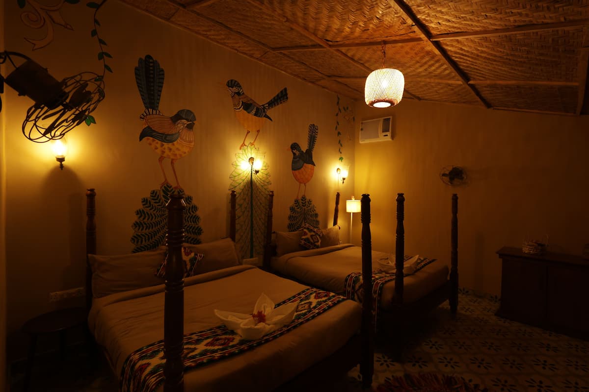 Una habitación tenuemente iluminada con dos camas, techo de madera y luces fijadas a la pared.
