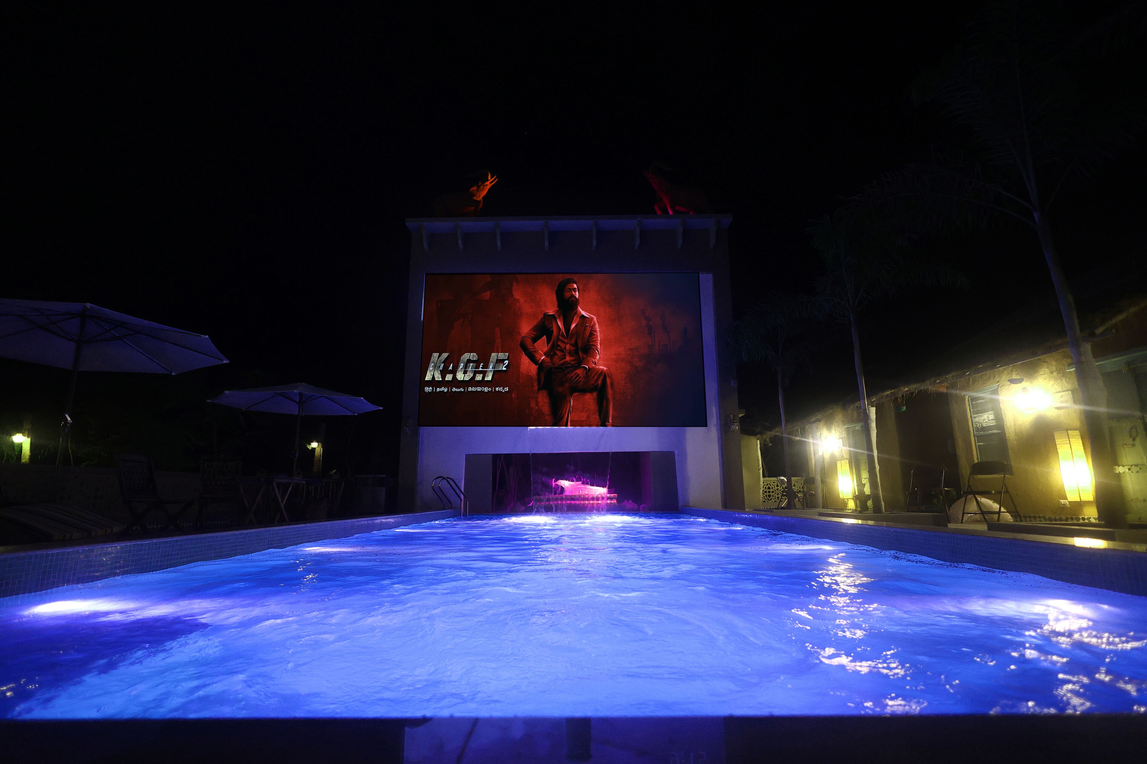 Une piscine avec un grand écran lumineux en arrière-plan, sur lequel est projetée l’image d’une personne.