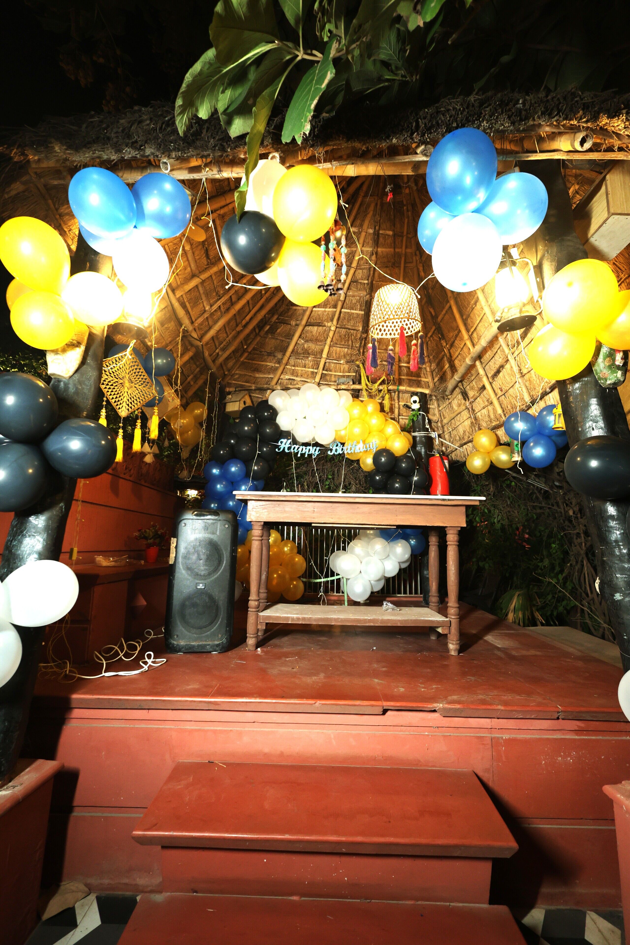 Een podium met een tafel, ballonnen en een spreker.
