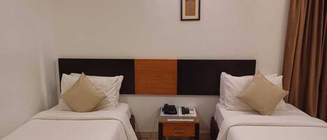 Una habitación de hotel con dos camas, una mesita de noche y un cuadro en la pared.