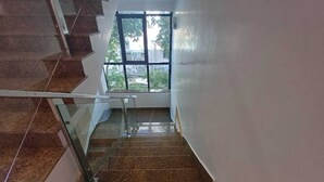 Una escalera con barandillas de vidrio que lleva a un rellano con un ventanal grande.