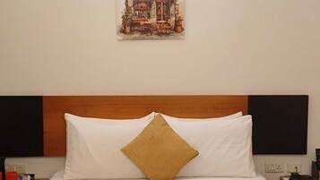 Habitació d'hotel amb un llit, una nitòria amb un telèfon i un quadre penjat a la paret.