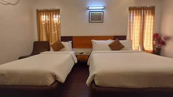 Habitación de hotel con dos camas, una mesita de noche, una silla y un cuadro colgado en la pared.