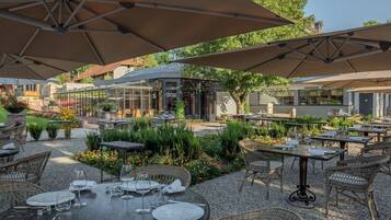 Dine al fresco under shaded umbrellas amidst lush greenery and modern architecture.