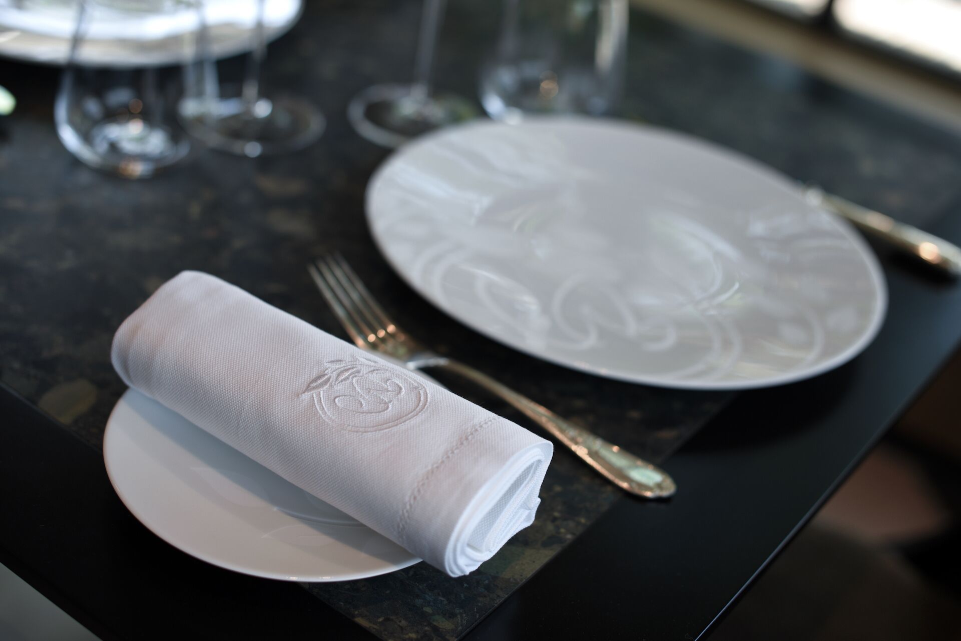 A neatly set dining table with a folded napkin, a fork, and a plate.