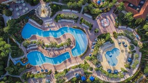 Een resort met meerdere zwembaden, ligbedden en palmbomen.