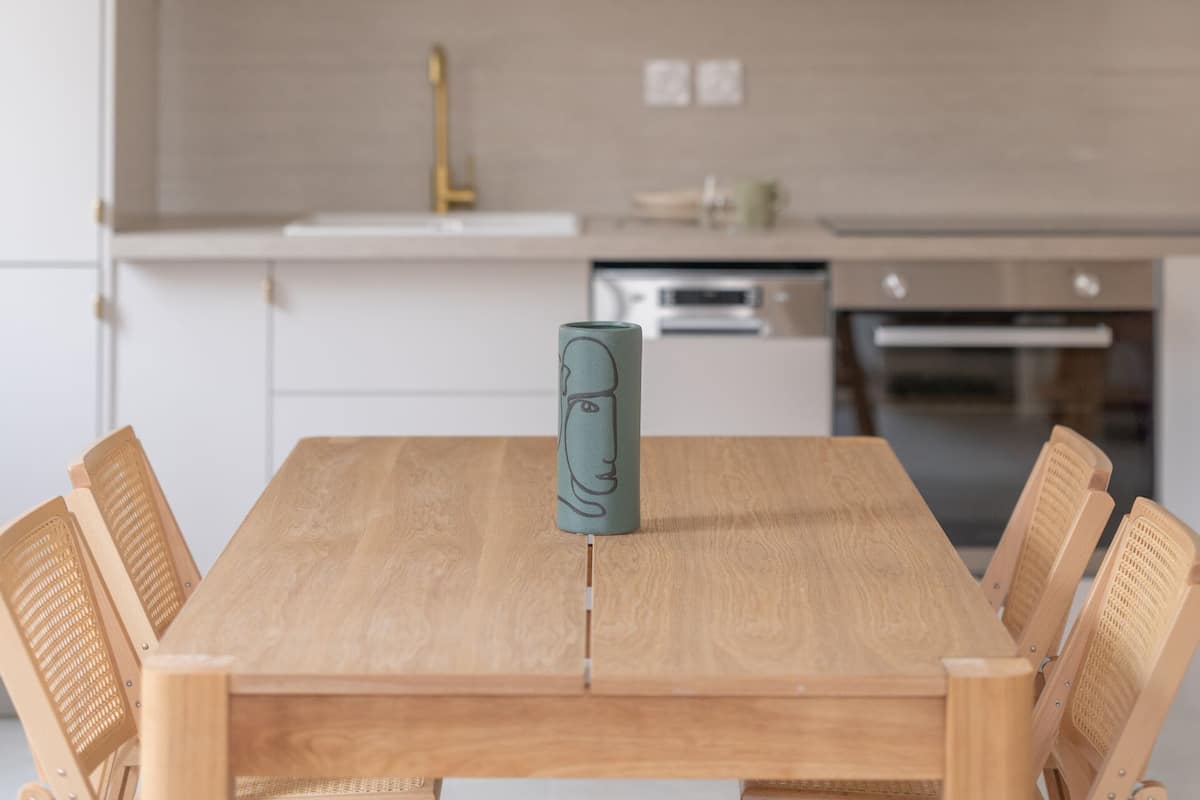 Een moderne eethoek met een houten tafel, zes stoelen en een hanglamp.