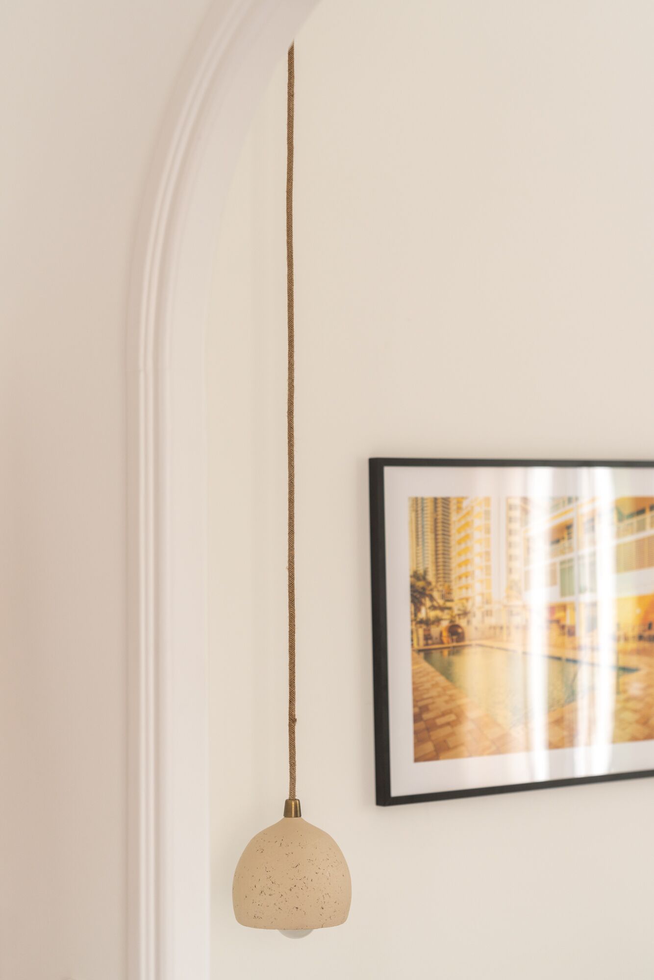 A pendant light with a textured shade hanging from a braided cord.