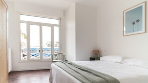 Ruime slaapkamer met een groot bed, uitzicht door een schuifdeur naar buiten en een ingelijst kunstwerk aan de muur.