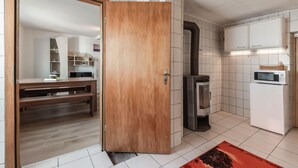 Et moderne køkken med hvide skabe, indbygget mikroovn og en brændeovn.