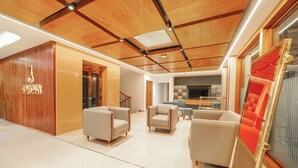 Ein modernes Interieur mit Holzboden, einer Rezeption und drei in einer Sitzecke angeordneten Sofas.