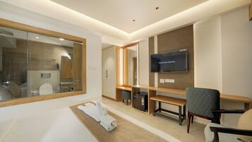 A modern hotel room with a large bed, a TV mounted on the wall, a desk, and a chair.