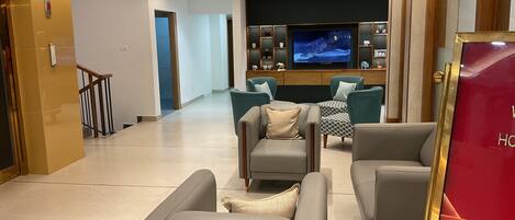Una sala de estar moderna con sofás grises y un televisor al fondo.