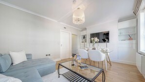 A modern living room with a sofa, a glass coffee table, and a dining area with chairs and a table. - Iconic Oxford Street Apartment ✨ 2 Bed 1 Bath ✨ Tube ✨ Bond Street 📍 (Greater London)