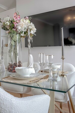 A dining table set with glassware, a white bowl, and a vase with flowers. - Iconic Oxford Street Apartment ✨ 2 Bed 1 Bath ✨ Tube ✨ Bond Street 📍 (Greater London)