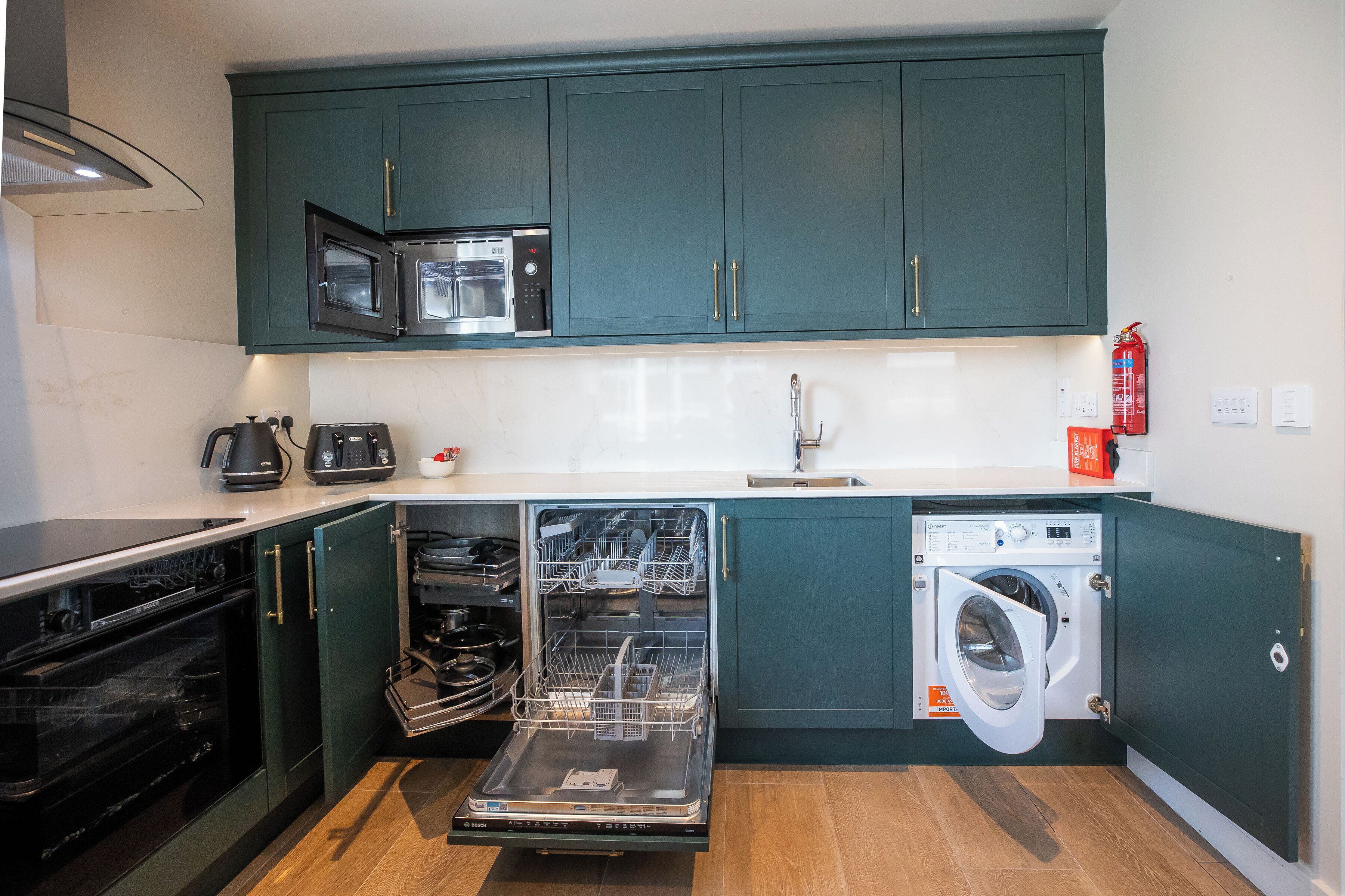 A compact kitchen with a built-in oven, microwave, dishwasher, and washing machine.