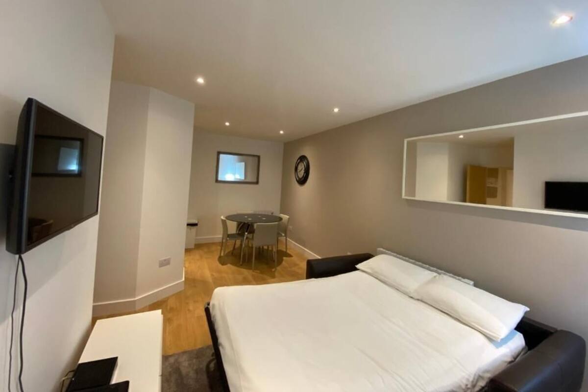 Une chambre d’hôtel moderne équipée d’un grand lit, d’un bureau, d’une chaise, d’une télévision et d’une petite table à manger.