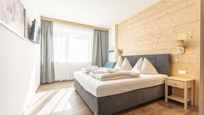 Et moderne soveværelse med en grå seng, træsengegavl og et lille natbord med en lampe.