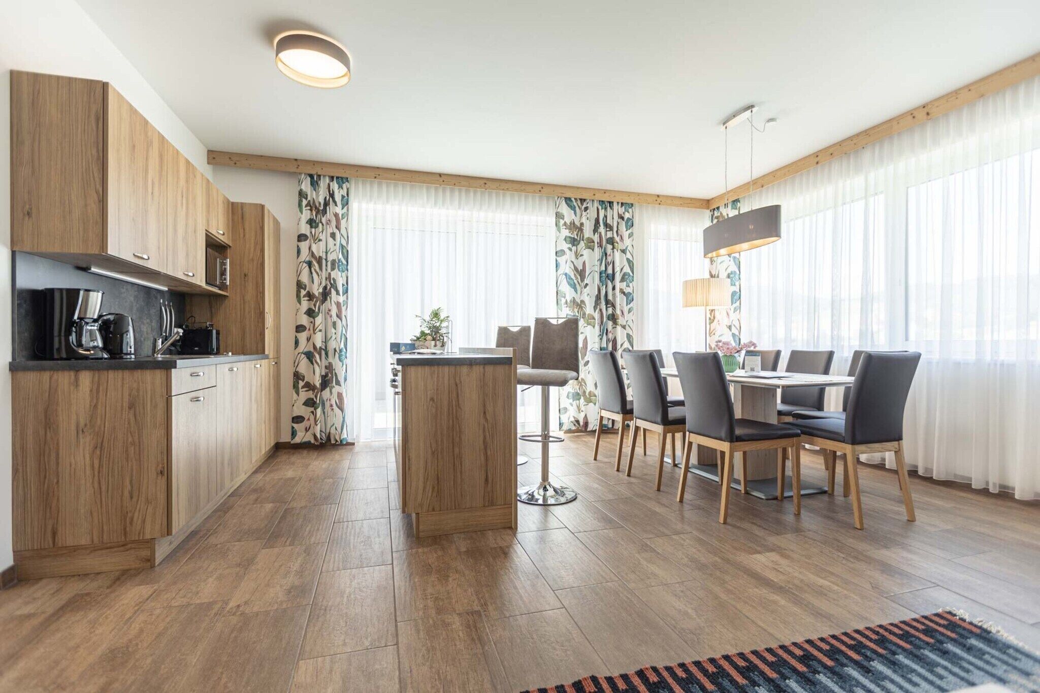 Eine moderne Küche mit Holzausstattung, einer zentralen Kochinsel und einem Essbereich mit Tisch und Stühlen.