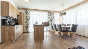 Et moderne køkken med træskabe, en central ø og et spiseområde med bord og stole.