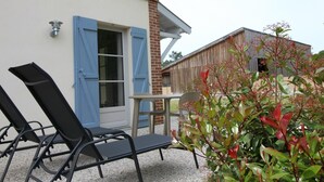 A patio with outdoor furniture, a wooden building with blue shutters, and a brick wall. - DOMAINE DU FLAMAND - Gite DUNE  (Naujac-sur-Mer)