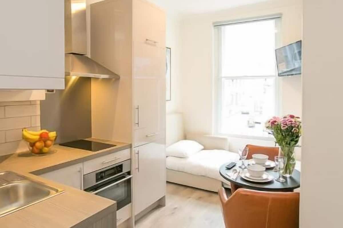 A compact kitchen with a dining area, a window with a view, and a small table with chairs.