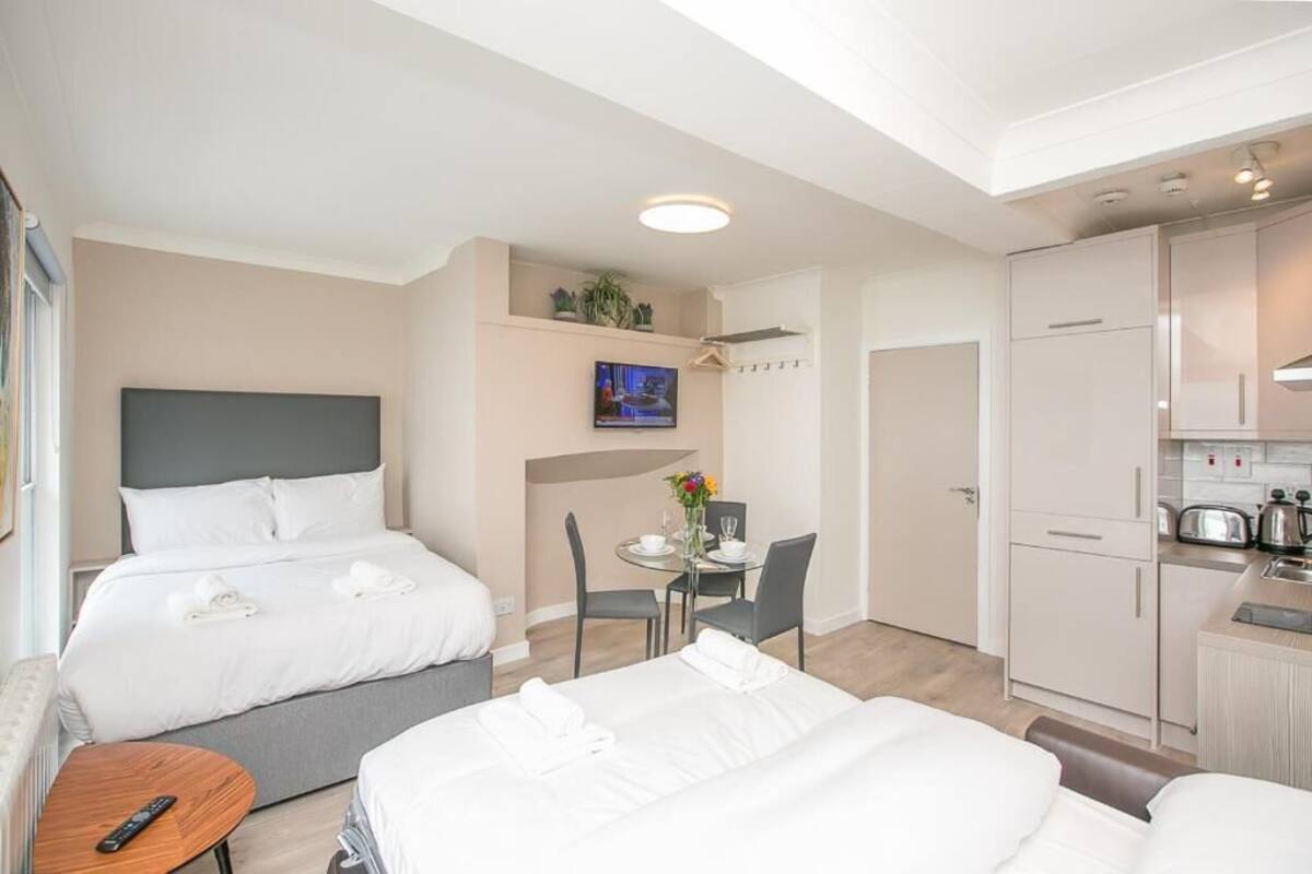 A hotel room with two beds, a dining area, and a kitchenette.