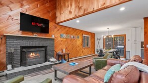 A cozy living room with a fireplace, leather sofa, and a flat-screen TV mounted above it.