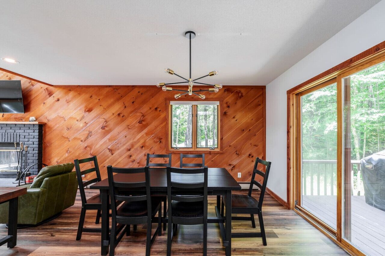 Un espace repas avec un mur en bois, une cheminée et une grande fenêtre.