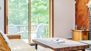 A cozy living area with a wooden coffee table, a sofa, and a sliding glass door leading to an outdoor deck with chairs.