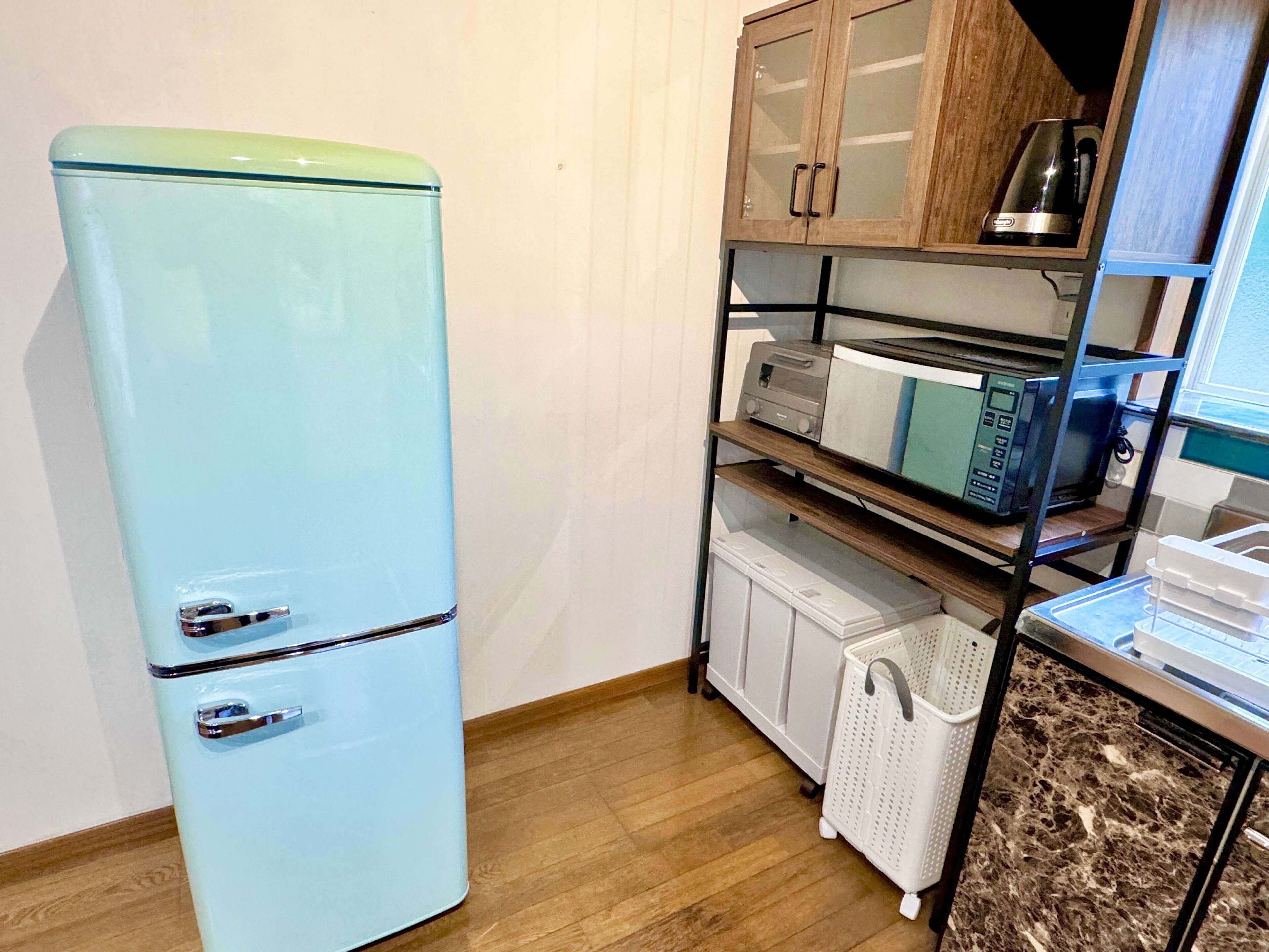 A compact kitchen with a light blue refrigerator, wooden cabinets, a microwave, and a coffee maker.