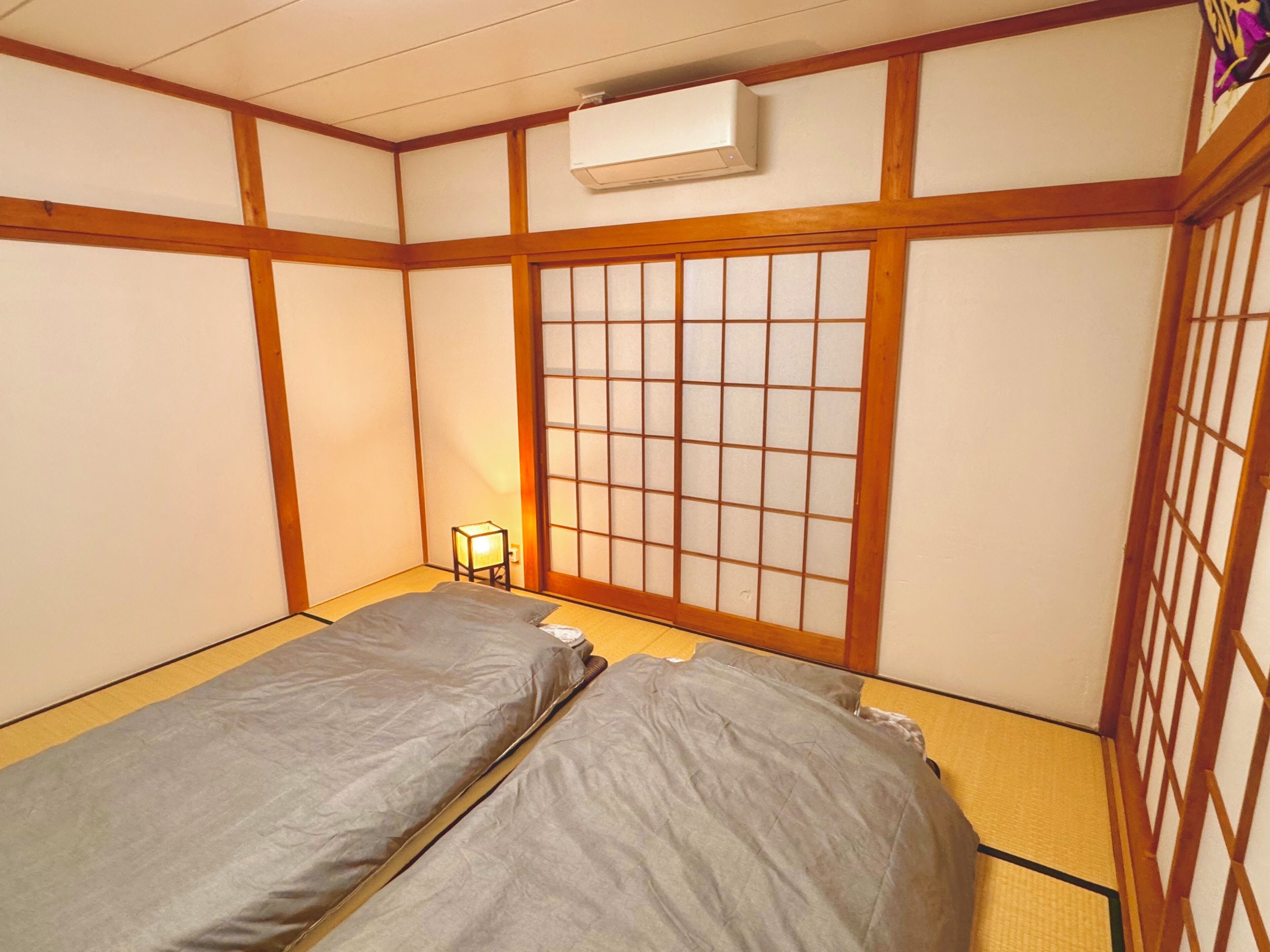 A traditional Japanese room with tatami flooring, a shoji screen, and a futon bed.