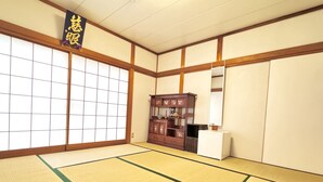 Una tradizionale stanza giapponese con pavimento in tatami, porte scorrevoli e un armadio in legno con vetrate.
