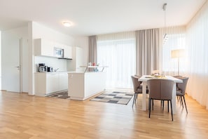 A modern kitchen with white cabinets, a microwave, and a dining area with a table and chairs.