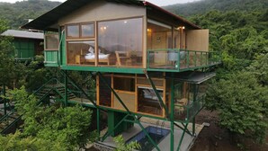 A two-story wooden cabin with glass windows, surrounded by lush greenery. - The Arboreal Resort (Mawal)